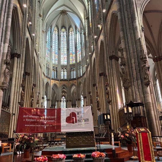 Das Banner der Aktion Neue Nachbarn im Kölner Dom zur Andacht mit Geflüchteten